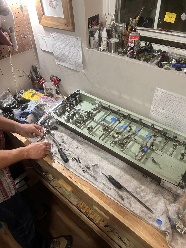 Brett at the bench fitting parts to a pedal steel's changer, its pull rods labelled with tape