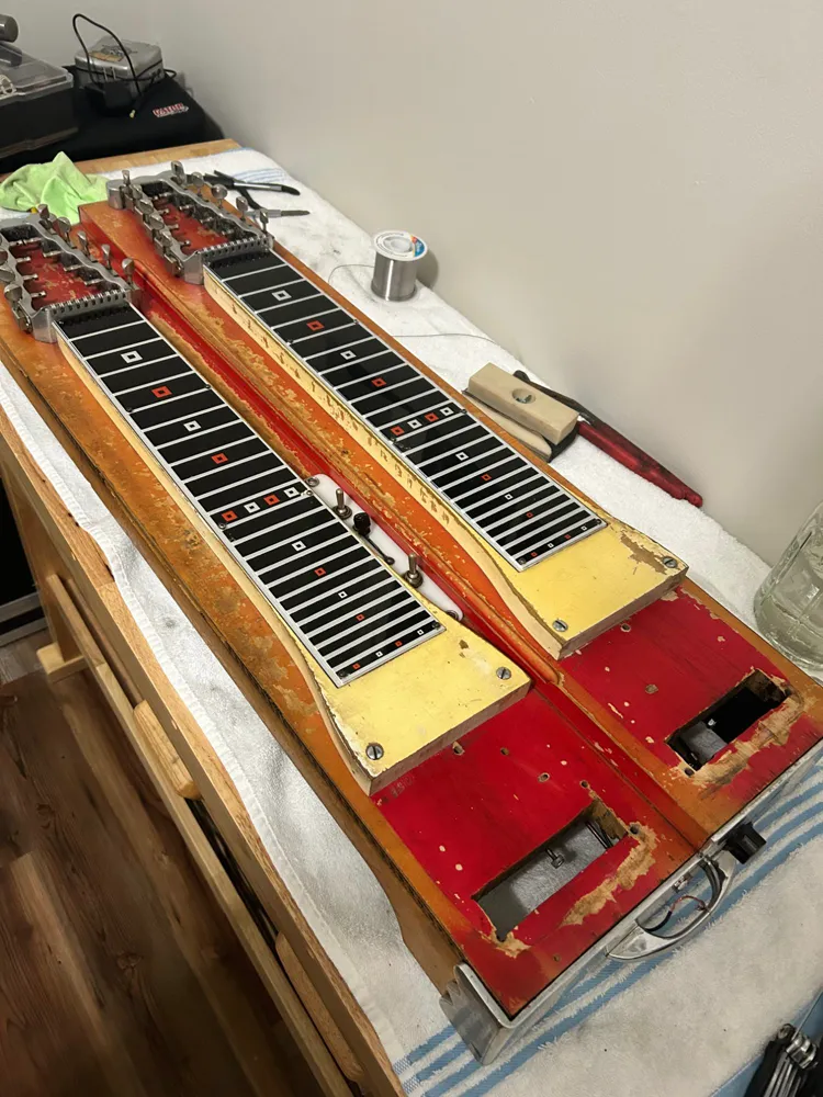 A double-neck steel guitar opened up on the workbench