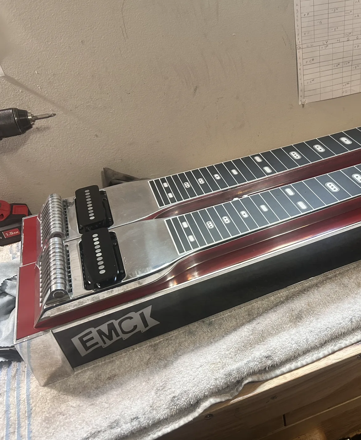 A red EMCI double-neck pedal steel on the bench