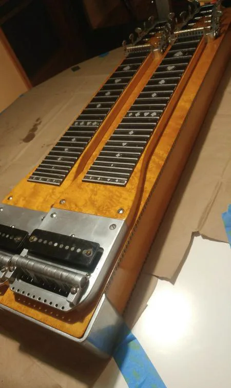 A maple double-neck steel guitar with its pickups and changer showing