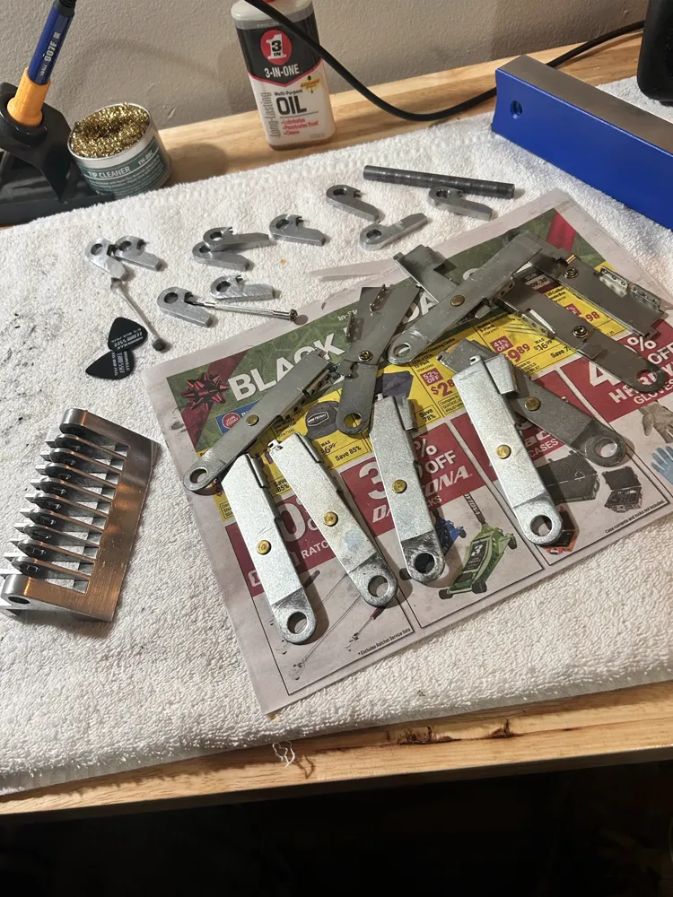 Pedal steel parts laid out on newspaper: pedal arms, knee levers, changer fingers