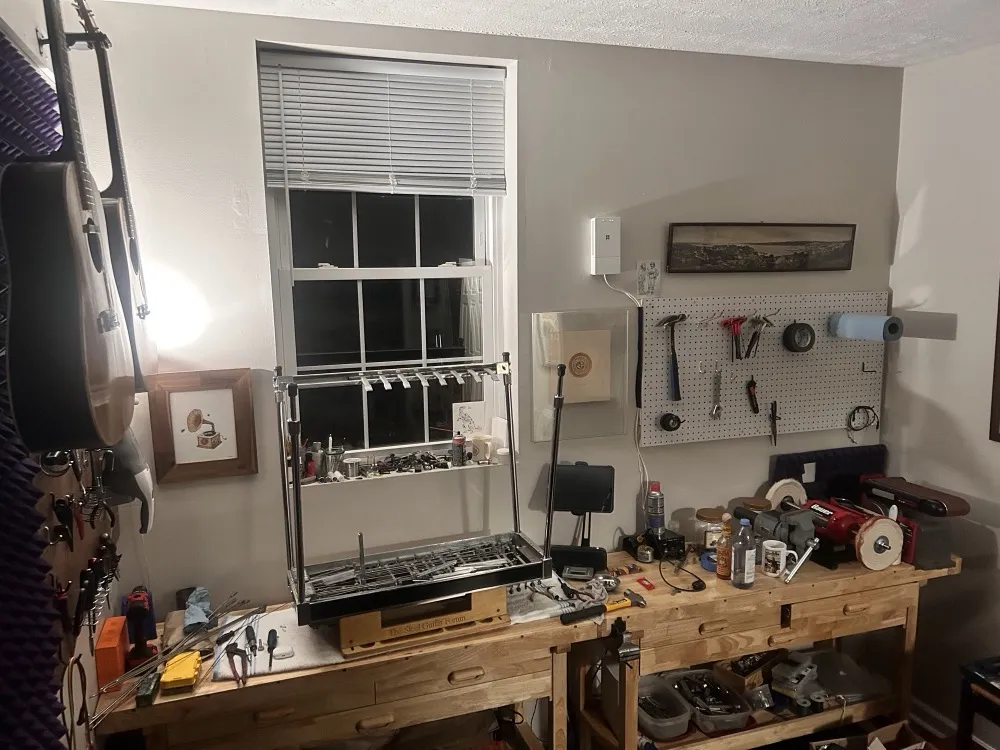 The workshop: a pedal steel upside down on the bench under the pegboard